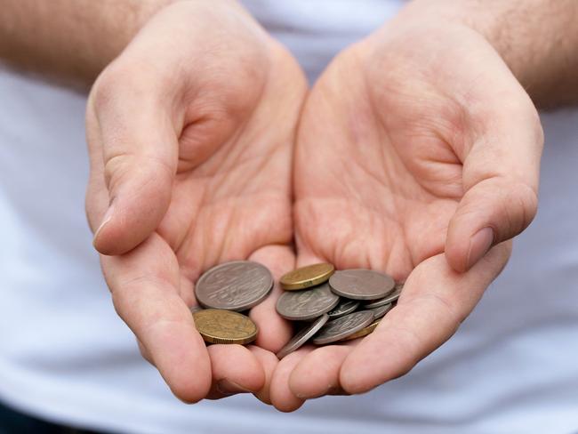 A caucasian man holds out some Australian coins; poor money generic hands