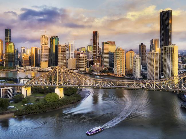 Developing Queensland - Close to Story Bridge across Brisbane River in front of Brisbane city CBD high-rise business and apartment towers with fast ferry on the water under the bridge.