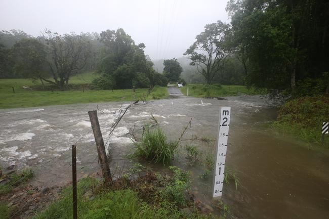 An abandoned police car sits on the other side of the water on Tallebudgera Creek Rd after police were left stranded by rising floodwaters and had to wait until morning to walk out. Picture: Glenn Hampson.