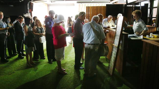 Punters line up to place at bet at Eagle Farm on Tuesday. The bookies had to use pencils and paper to write their tickets. Picture: Liam Kidston