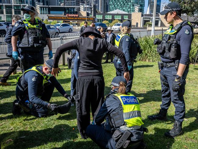 Police search a protester. Picture: Jake Nowakowski