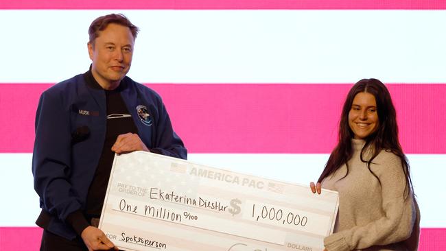 Elon Musk presents a check for $1 million dollars. Picture: AP Photo/Jeffrey Phelps