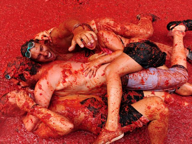 Revellers lay in tomato pulp during the world's biggest tomato fight at La Tomatina festival. Picture: Jasper Juinen/Getty Images