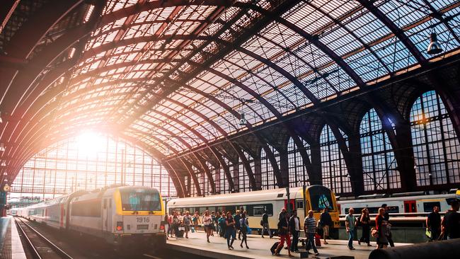 Trains and people boarding in the beautiful Antwerpen train station.