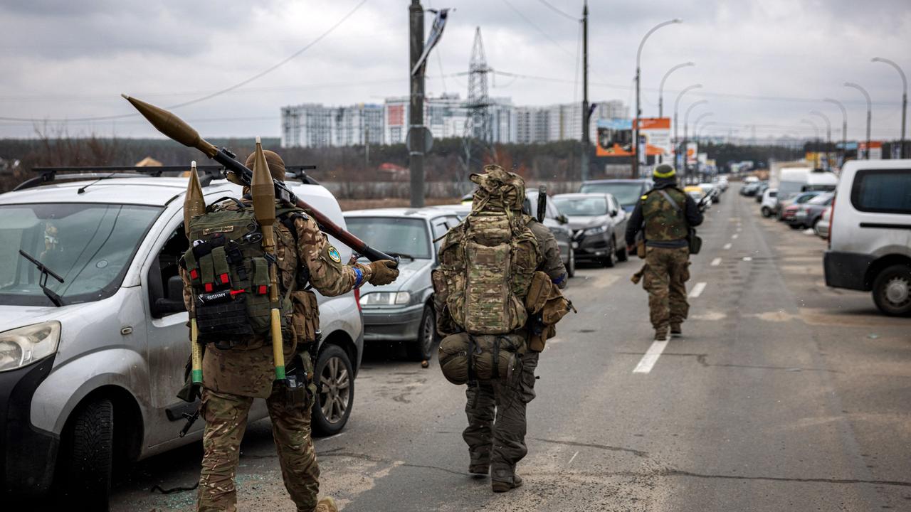 Ukrainian servicemen carry rocket-propelled grenades and sniper rifles as they walk towards the city of Irpin, northwest of Kyiv. Picture: AFP