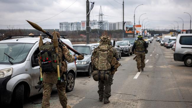 Ukrainian servicemen carry rocket-propelled grenades and sniper rifles as they walk towards the city of Irpin, northwest of Kyiv. Picture: AFP