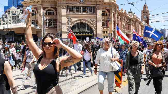 Demonstrators walking up Flinders St past the iconic train station on November 27. Picture : Ian Currie