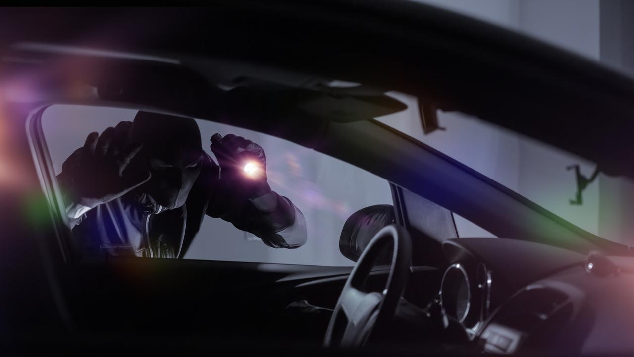 Car robber with flashlight looking inside the car. Picture: iStock