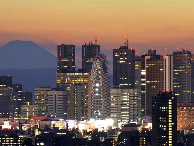 Japan's highest mountain Mount Fuji rises up behind the skyscraper skyline of Tokyo.