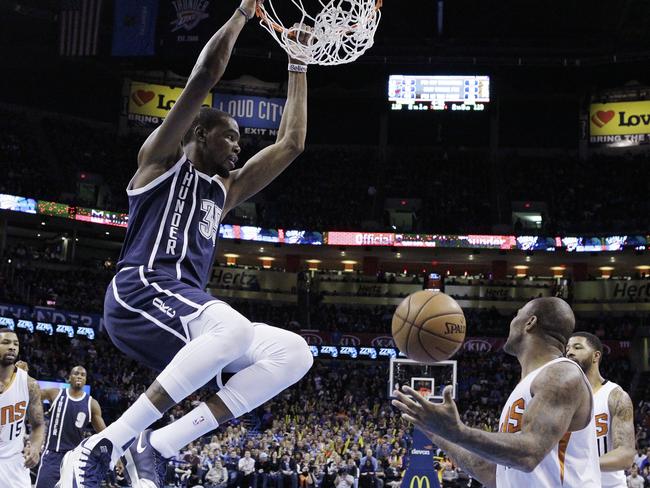 Thunder forward Kevin Durant hangs from the basket after dunking in front of Marcus Morris of the Suns.