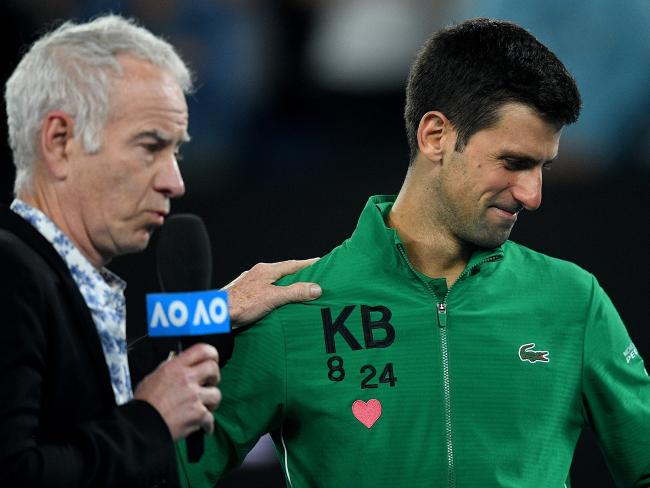 An emotional Novak Djokovic is comforted by  John McEnroe .