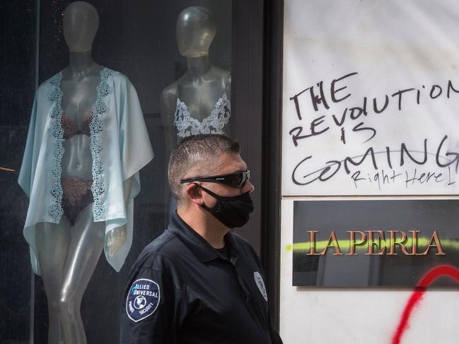 A security member walks past graffiti saying 'The Revolution is Coming' outside a store on the iconic Rodeo Drive in Los Angeles. Picture: AFP