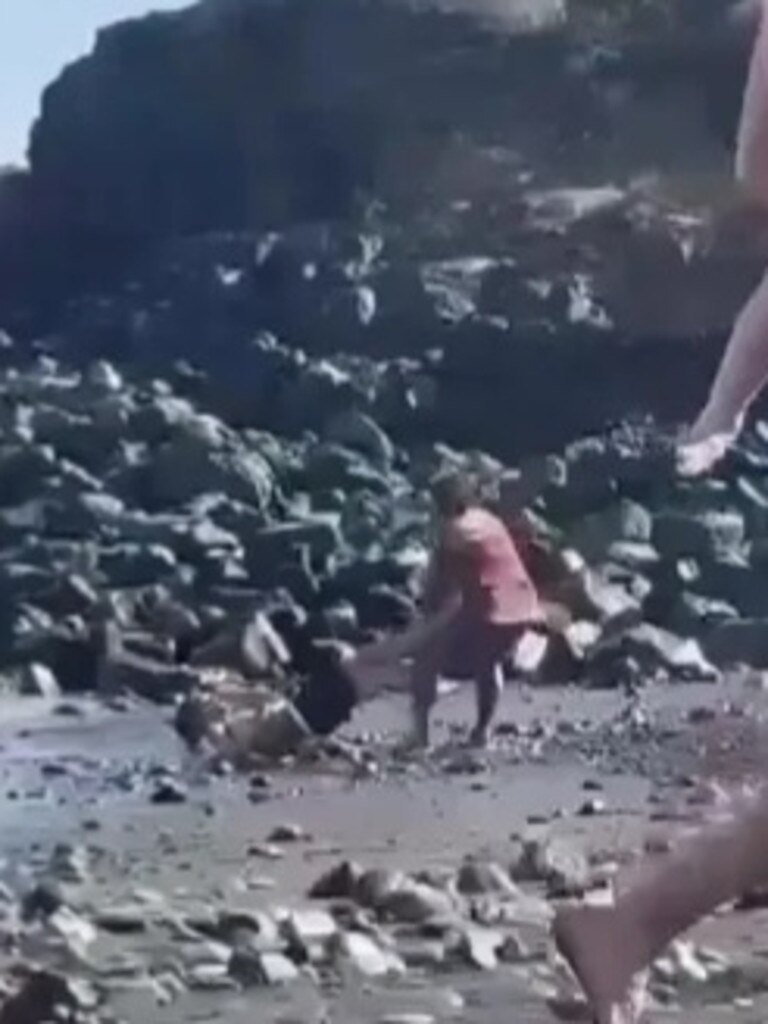 The victim rolls down the beach while the man continuously pelts him with a pole. Picture: Facebook