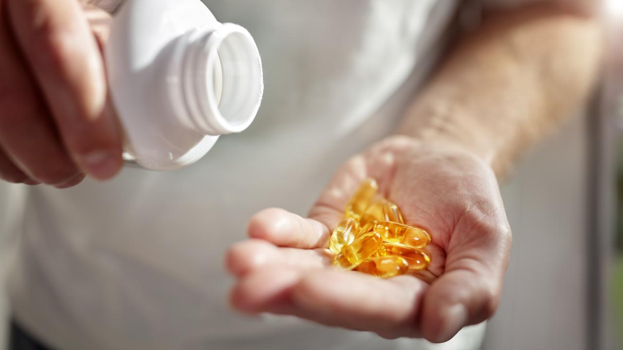 Bottle of omega 3 fish oil capsules pouring into hand