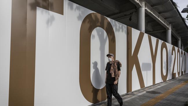 A man wearing a face mask walks past Olympics branding outside of the New National Stadium, the main stadium for the Tokyo Olympics. Tokyo 2020 president Seiko Hashimoto has stated that she is 100 per cent certain that the Olympics will go ahead despite widespread public opposition as Japan grapples with a fourth wave of coronavirus. Picture: Yuichi Yamazaki/Getty Images