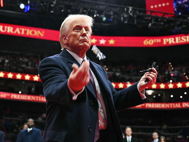 TOPSHOT - US President Donald Trump throws pens to the crowd after signing executive orders during the inaugural parade inside Capital One Arena, in Washington, DC, on January 20, 2025. (Photo by Jim WATSON / AFP)