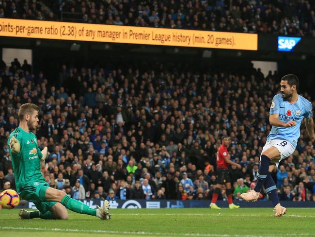 Manchester City's German midfielder Ilkay Gundogan (R) shoots and scores their third goal past Manchester United's Spanish goalkeeper David de Gea during the English Premier League football match between Manchester City and Manchester United at the Etihad Stadium in Manchester, north west England, on November 11, 2018. (Photo by Lindsey PARNABY / AFP) / RESTRICTED TO EDITORIAL USE. No use with unauthorized audio, video, data, fixture lists, club/league logos or 'live' services. Online in-match use limited to 120 images. An additional 40 images may be used in extra time. No video emulation. Social media in-match use limited to 120 images. An additional 40 images may be used in extra time. No use in betting publications, games or single club/league/player publications. /