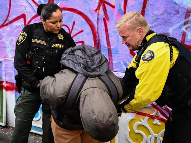 Portland Police officer Eli Arnold (R) conducts an investigation into drug dealing before issuing a citation for drug possession in downtown Portland, Oregon on January 25, 2024. When police officer Eli Arnold stops a homeless man smoking methamphetamine on the street in Portland, he simply writes him a ticket with a $100 fine. Since hard drugs were decriminalised in Oregon three years ago, there are no arrests, just the fine and a card with a telephone number where the user can get help. "Give them the ticket number and they'll just ask you if you want treatment," he tells the man. There's no wrong answer to this question, he says. "Just call the number, the ticket goes away." In February 2021, possession and use of all drugs -- including cocaine, heroin, ecstasy and fentanyl -- was decriminalised in the western state. Sale and production remains punishable. (Photo by Patrick T. Fallon / AFP)