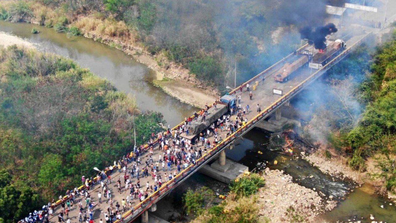 This disturbing photo of the Venezuela crisis shows civilians clashing with government troops as aid trucks are burned and destroyed. 