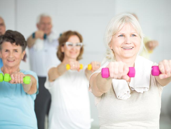 Elderly women holding dumbbells during group exercise class for senior citizens