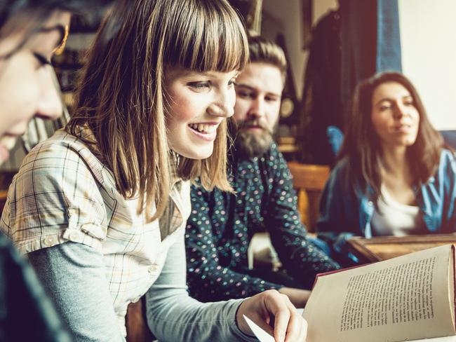 Friends reading books and studying for exam together