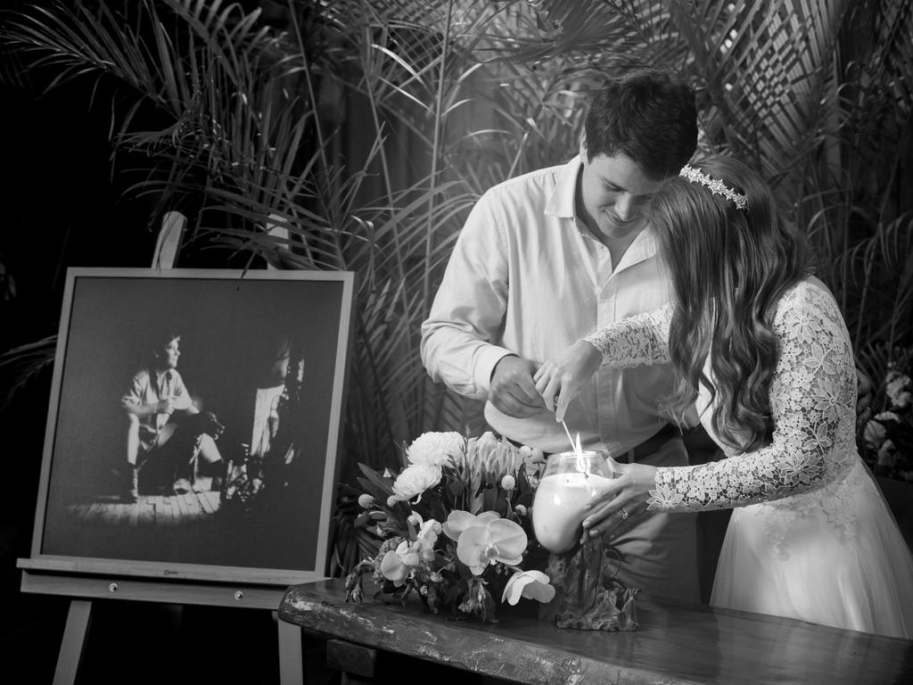 Chandler Powell and Bindi Irwin lighting a candle next to an easel with a photograph of Steve Irwin. Picture: Kate Berry