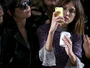 LONDON, ENGLAND - FEBRUARY 22:  Alexa Chung takes a photo on her phone while watching the TopShop unique show during London Fashion Week Fall/Winter 2015/16 on February 22, 2015 in London, United Kingdom.  (Photo by Danny Martindale/WireImage)