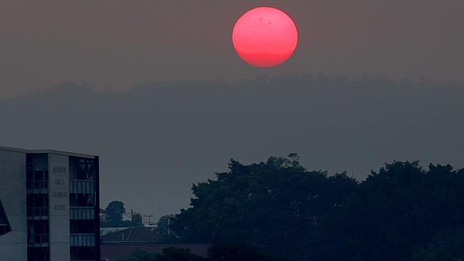 Frightening ... A bushfire on Stradbroke Island turns a setting sun red over Brisbane. Picture: Marc Robertson