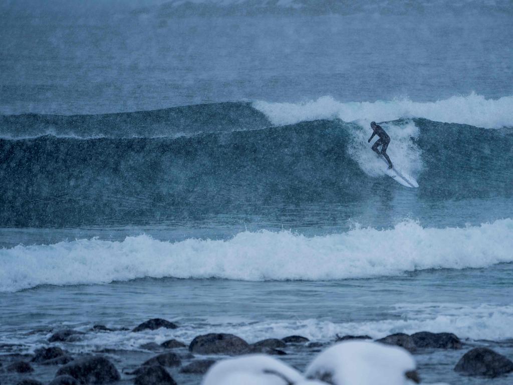 A surfer rides waves under snowfall on March 11, 2018, in Unstad, northern Norway, Lofoten islands, within the Arctic Circle as air temperature drops minus 13°C and water temperature above 4°C. Picture: AFP