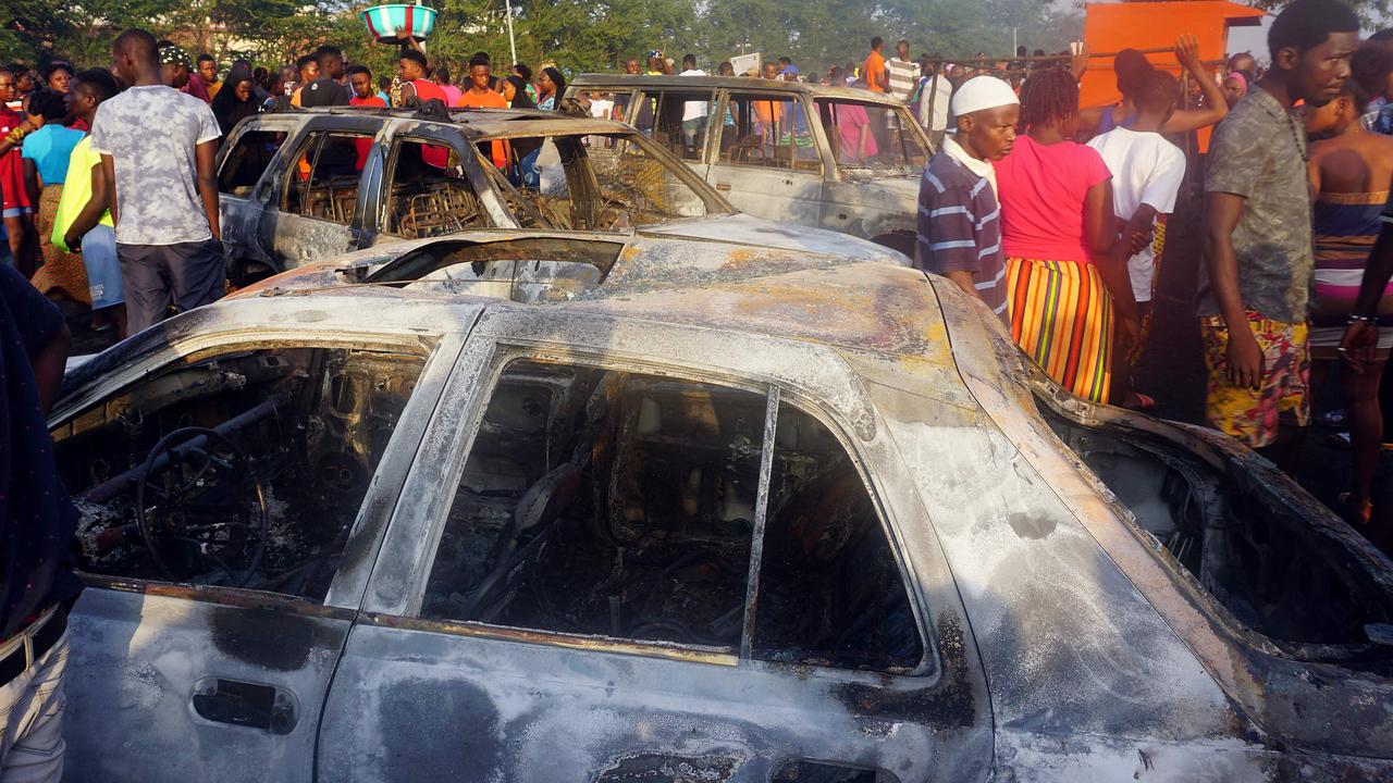 People look on at burnt cars in the aftermath of the fuel tanker explosion. Picture: Saidu BAH / AFP.