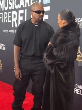 Kanye West can be seen telling Bianca Censori to drop her coat on the Grammys red carpet. Picture: CBS