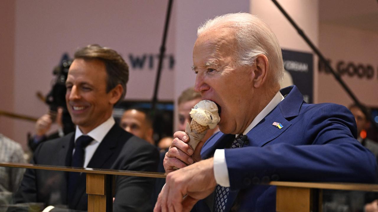US President Joe Biden, flanked by host Seth Meyers, eats an ice cream cone at Van Leeuwen Ice Cream after taping an episode of 