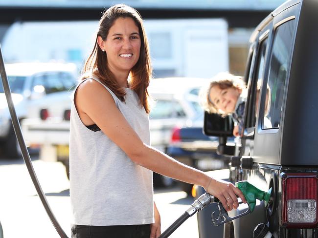 Jess Walker of Newtown fills up her car with petrol as her son Lachlan watches on at Bargain Petrol station in Erskineville, Sydney. This station has the cheapest petrol around. Picture: Brett Costello