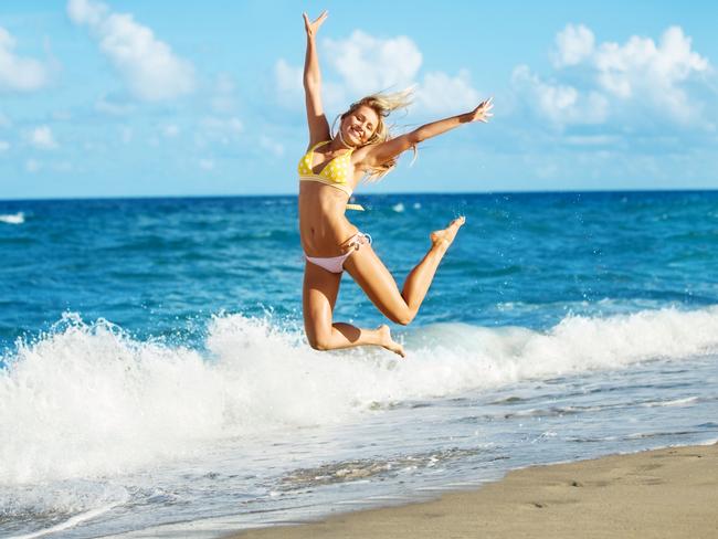 Young attractive woman jumping for joy at a beautiful Beach.