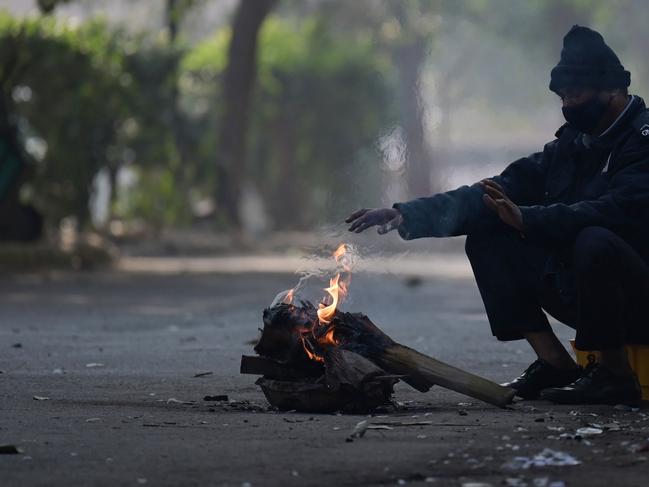 A man warms himself near a fire along an alley in New Delhi as the city grapples with a surge in coronavirus cases. Picture: AFP