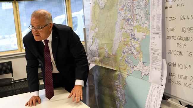 Scott Morrison takes a look at a map of the south coast area impacted by bushfire during an operational update at HMAS Albatross in Nowra on Sunday. Picture: AAP