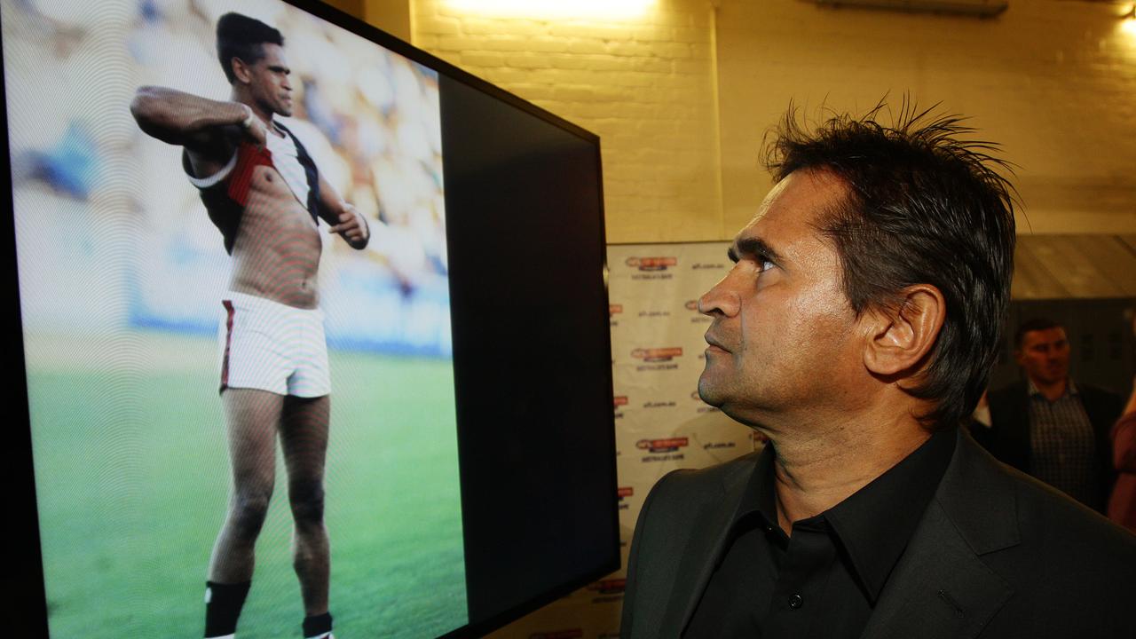 Nicky Winmar looks at the iconic photo of him pointing towards his skin, in defiance, after being abused during a game against Collingwood in 1993.