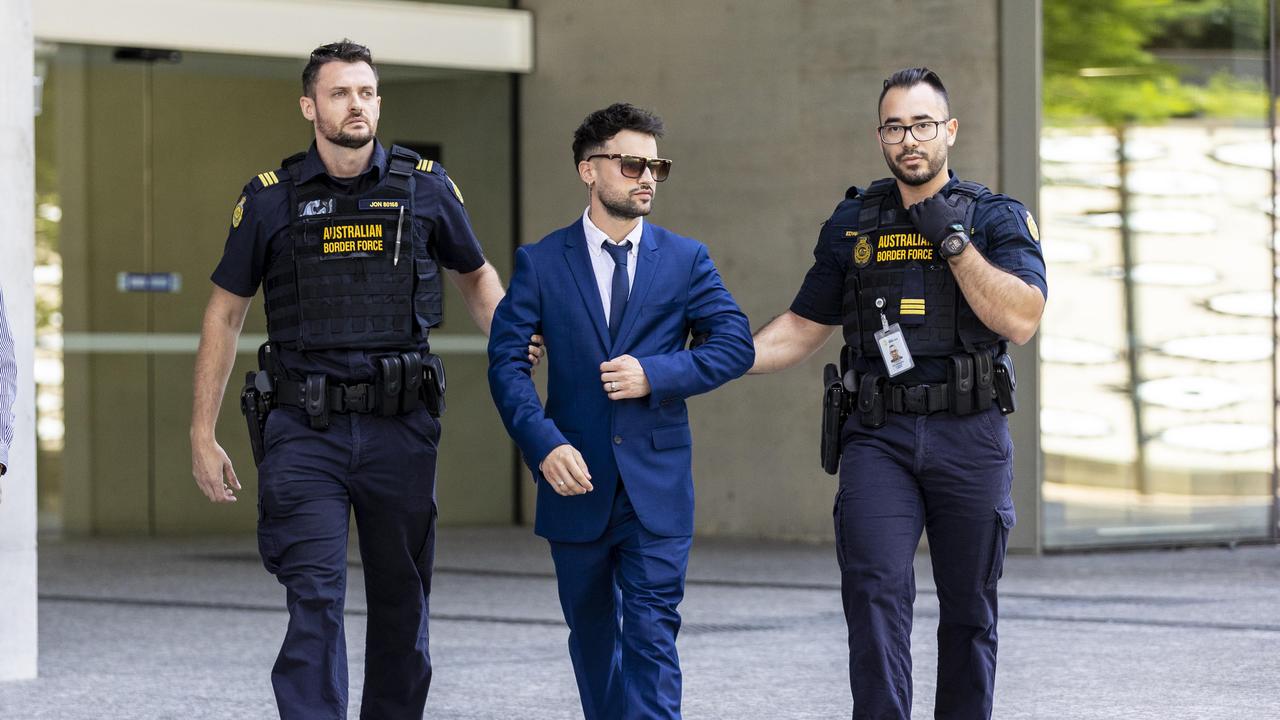 Giovanni Genuario is taken away by Australian Boarder Force officers.