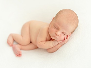 Dreamy newborn baby sleeping peacefully on the side on bed