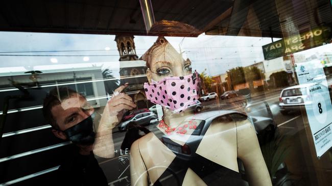 A shopkeeper places a mask on a display mannequin at the Club X shop in Brunswick in Melbourne on July 23. Picture: Getty