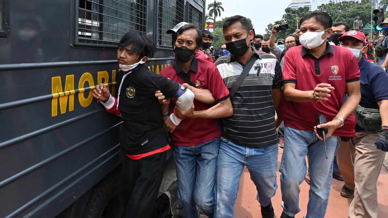 Police arrest a man during a rally against high prices of supplies, postponement of presidential elections and an extension of the President's term in Jakarta on April 11, 2022. (Photo by ADEK BERRY / AFP)