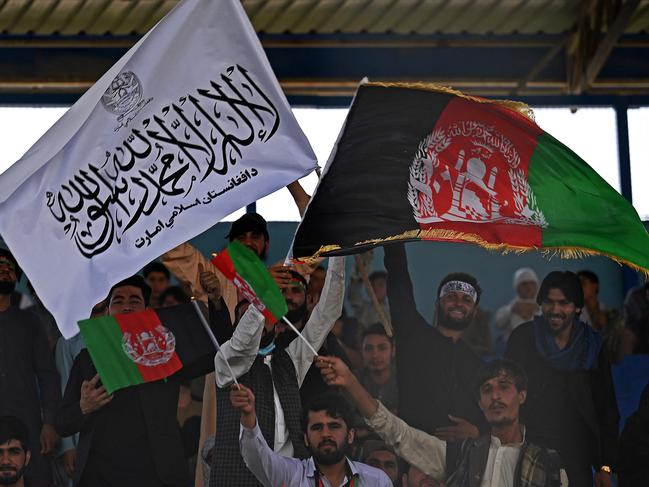 Spectators wave Afghanistan's and Taliban flags as they watch the Twenty20 cricket trial match being played between two Afghan teams 'Peace Defenders' and 'Peace Heroes' at the Kabul International Cricket Stadium in Kabul on September 3, 2021. (Photo by Aamir QURESHI / AFP)