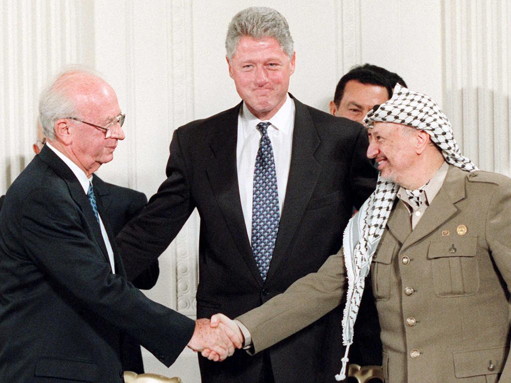 Israeli Prime Minister Yitzhak Rabin shaking hands with Palestinian leader Yasser Arafat at the White House, watched by President Bill Clinton after signing peace accord in 1993.