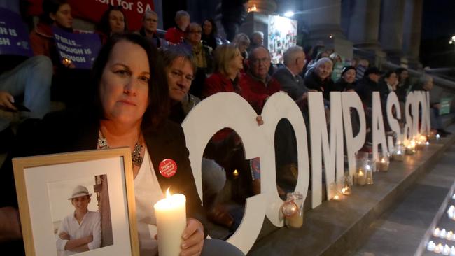 Liz Habermann, with her husband Bret, holds a photo of their son Rhys at a Parliament House vigil, during the height of the assisted dying legislation debate last year. Picture: Kelly Barnes