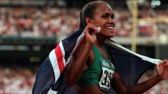 Cathy Freeman drapes herself in the Australian flag after running her fastest time in the 400m