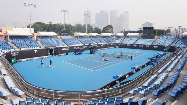 The city’s skyline, viewed from a tennis court at Melbourne Park, is shrouded by smoke haze this morning. Picture: AAP