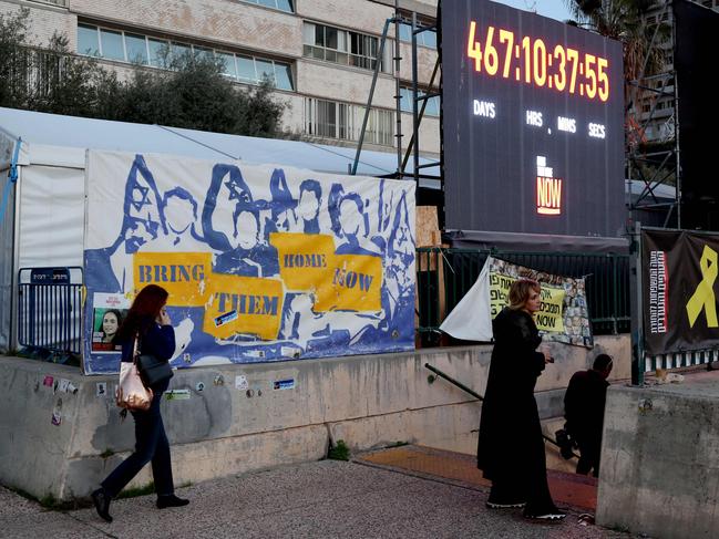 People walk past an installation consisting of a clock counting the time hostages held in the Gaza Strip since the October 7, 2023 attack by Hamas militants have spent in captivity, set up on a square outside the Tel Aviv Museum of Art, now informally called the "Hostages Square", in Tel Aviv on January 16, 2025. Israel said on January 15 that several points in the Gaza ceasefire and hostage release deal still needed to be resolved but expected them to be finalised  even as news spread that an agreement with Hamas had been reached. (Photo by Jack GUEZ / AFP)