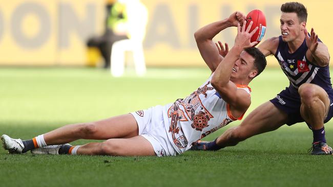 Jake Riccardi of the Giants handballs over his head against Ethan Hughes of the Dockers during the round-14 AFL match between Fremantle and the Greater Western Sydney at Optus Stadium on Saturday. Picture: Paul Kane/Getty Images