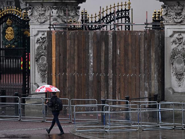 People walk past the a set of boarded up gates to Buckingham Palace in London on March 10, 2024, after a car crashed into them. Officers have arrested a man. Picture: AFP