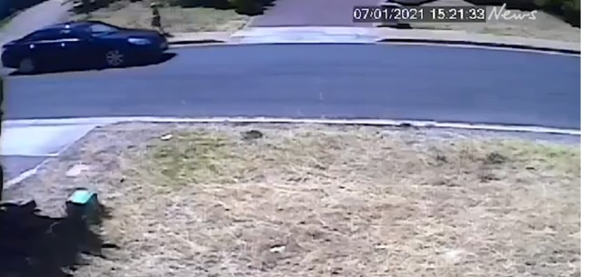 The car is seen approaching the boy while he rides his scooter.